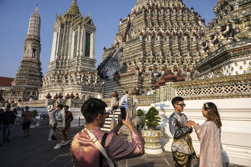 Khách du lịch trong trang phục truyền thống Thái Lan chụp ảnh tại chùa Wat Arun ở Bangkok, Thái Lan. Ảnh: Bloomberg