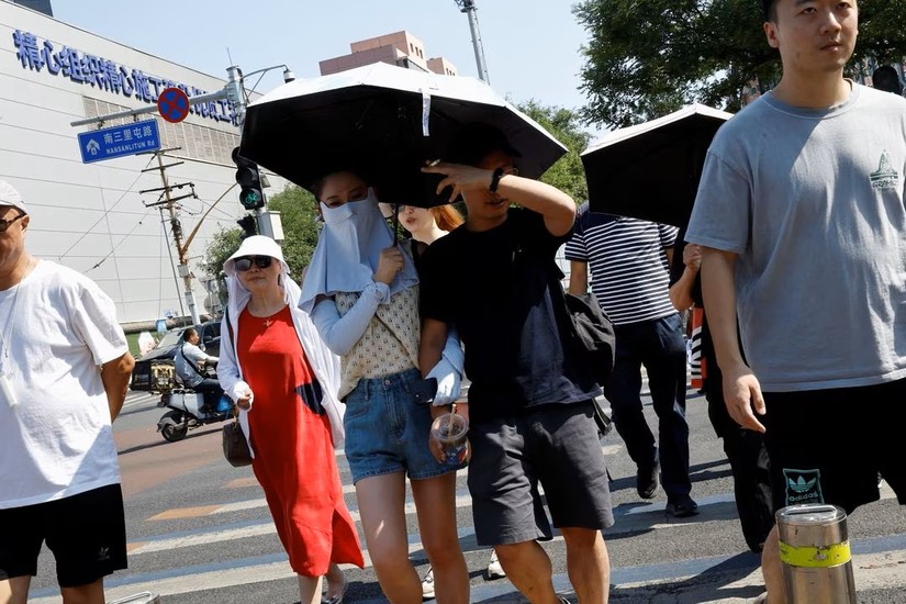 Người dân Bắc Kinh che chắn khi xuất hiện ngoài trời nắng nóng. Ảnh: Reuters